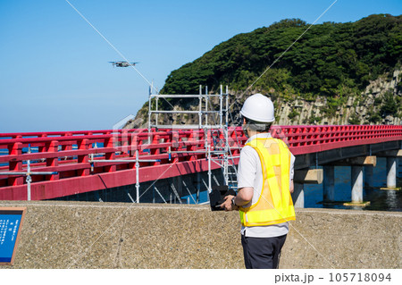 橋梁点検のためドローンを操縦する男性作業員|ドローン点検イメージ 橋梁点検のためドローンを操縦する男性作業員|ドローン点検イメージ 105718094
