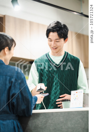 スキャナーを持ってスマホのバーコードを読む若い男性 スキャナーを持ってスマホのバーコードを読む若い男性 105721324