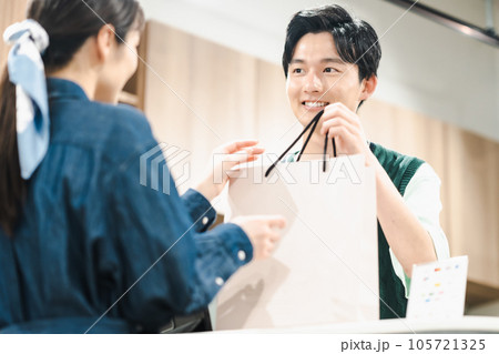 お店でお客様に商品を渡す男性店員 お店でお客様に商品を渡す男性店員 105721325