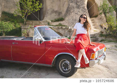 beautiful happy girl in a skirt posing near a retro car in the mountains of cappadocia 105724686