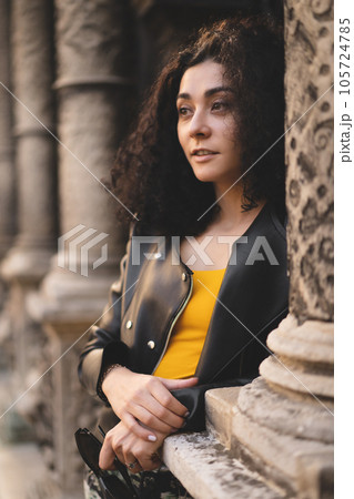 a beautiful girl in a leather jacket poses against the background of the city. a beautiful girl in a leather jacket poses against the background of the city. 105724785