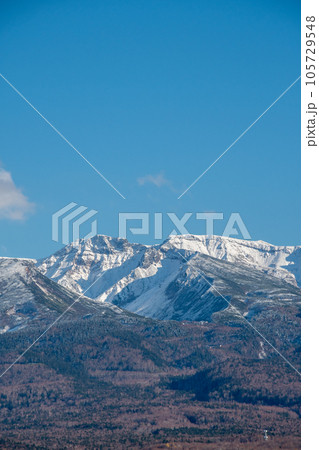冠雪の山並みと秋の森林 105729548