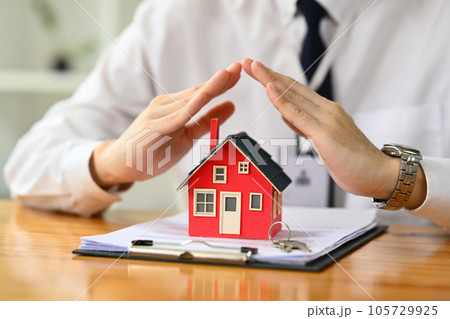 Man hands protecting over little house. Property insurance, security and real estate concept 105729925