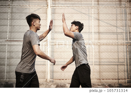 two young asian athletes giving hi-five celebrating success two young asian athletes giving hi-five celebrating success 105731314