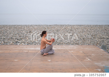 Caucasian man with naked torso practicing wushu on the seashore.  105732007