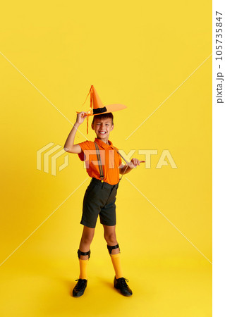 Full-length portrait of cheerful little boy, child in stylish clothes posing with smile against yellow studio background Full-length portrait of cheerful little boy, child in stylish clothes posing with smile against yellow studio background 105735847