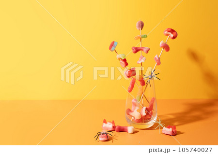 Marmalade on sticks in a glass cup against an orange background 105740027