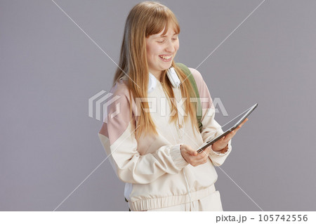 happy trendy teenager girl in beige tracksuit using tablet PC happy trendy teenager girl in beige tracksuit using tablet PC 105742556