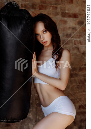 Awoman with an athletic build on the background of a punching bag 105742881