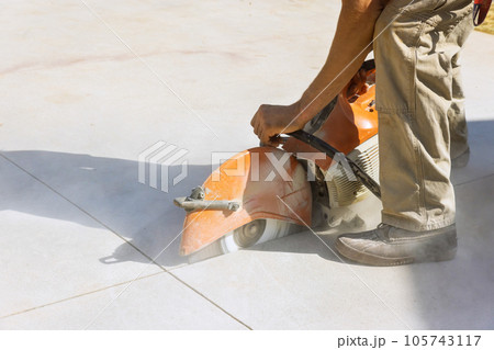 Contractor Worker Utilizes Diamond Blade Saw to Cut Concrete Paving Sidewalk 105743117