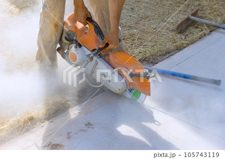 Concrete Paving Sidewalk Cutting by Skilled Construction Worker with Diamond Blade Saw 105743119