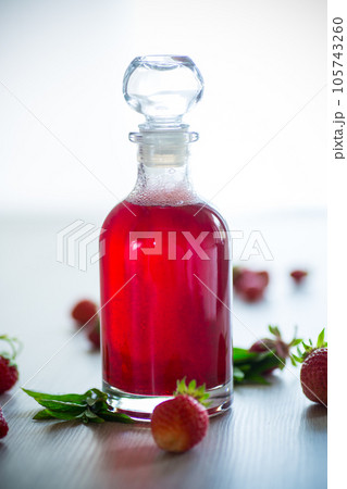 sweet cooked strawberry syrup in a glass decanter 105743260
