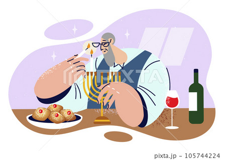 Elderly jewish man lights candles in minor before dinner and prepares to celebrate Hanukkah or Purim 105744224