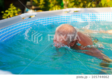 An elderly man bathes in a pool.  105744662