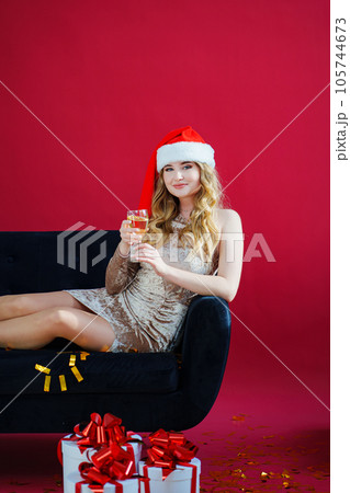 woman in santa hat with champagne and sparklers in red room on sofa with canfeti woman in santa hat with champagne and sparklers in red room on sofa with canfeti 105744673