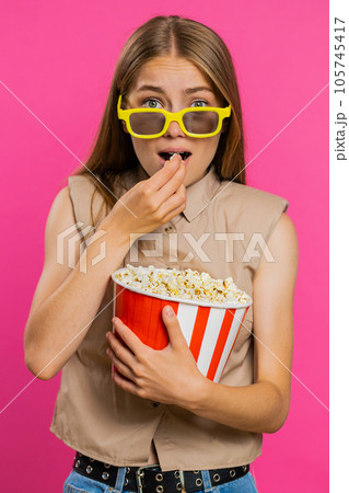 Woman in 3D glasses eating popcorn and watching interesting tv serial, sport game film, online movie Woman in 3D glasses eating popcorn and watching interesting tv serial, sport game film, online movie 105745417