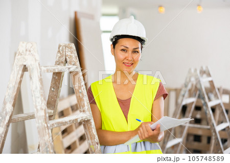 Positive woman builder with documents during repair works Positive woman builder with documents during repair works 105748589