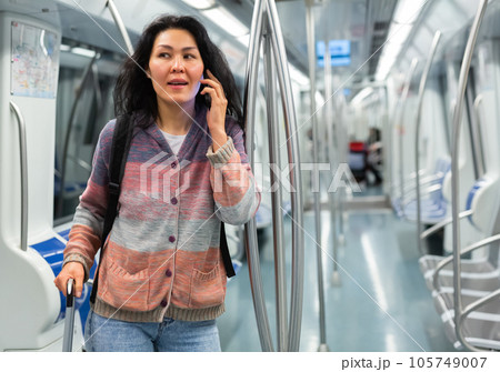 Oriental woman using smartphone while standing inside subway train and waiting for stop Oriental woman using smartphone while standing inside subway train and waiting for stop 105749007