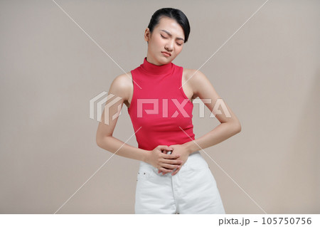 Asian woman suffering from stomach pain on beige background Asian woman suffering from stomach pain on beige background 105750756