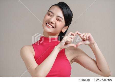 Pretty romantic young asian woman making a heart gesture with her fingers in front of her chest 105750769