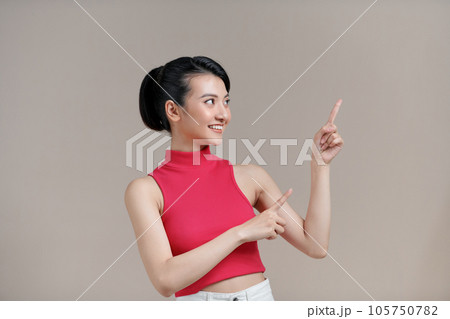 pretty woman smiling and pointing to side and upwards with both hands showing object in copy space 105750782