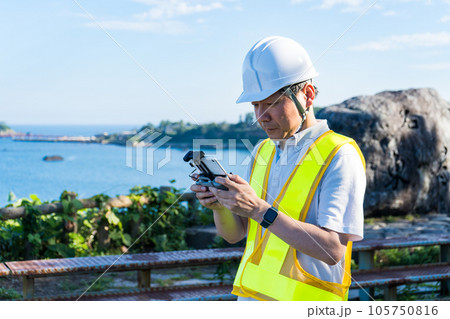 海辺でドローンを操縦する男性作業員|ドローンイメージ|点検イメージ 海辺でドローンを操縦する男性作業員|ドローンイメージ|点検イメージ 105750816