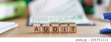 Word audit collected from wooden cubes and auditor working with documents in background. Word audit collected from wooden cubes and auditor working with documents in background. 105751111