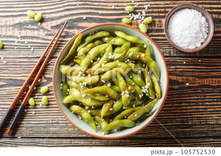 Japanese appetizer of fried edamame beans seasoned with coarse sea salt close-up on a plate. Horizontal top view Japanese appetizer of fried edamame beans seasoned with coarse sea salt close-up on a plate. Horizontal top view 105752530