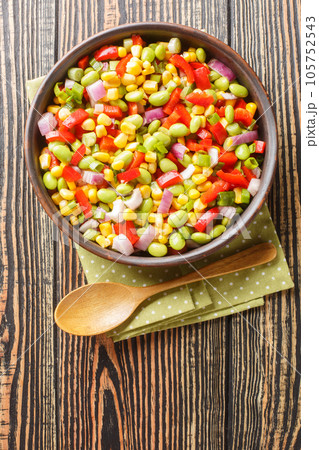 Summer vegetable salad with edamame beans close-up in a bowl. Vertical top view 105752543