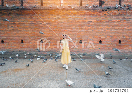 Young asian woman traveler in Yellow dress with hat and bag traveling on Tha Pae Gate, Tourist visit at the old city in Chang Mai, Thailand. Asia Travel, Vacation and summer holiday concept Young asian woman traveler in Yellow dress with hat and bag traveling on Tha Pae Gate, Tourist visit at the old city in Chang Mai, Thailand. Asia Travel, Vacation and summer holiday concept 105752792