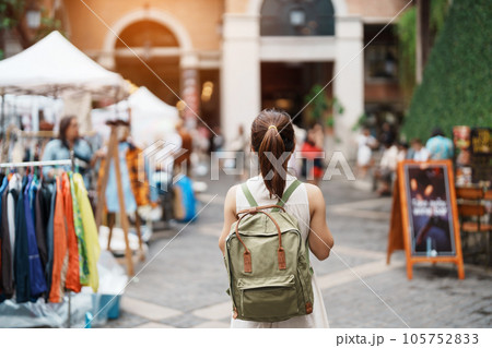 Young asian woman traveler in Yellow dress with bag traveling to NIMMAN on Nimmanhaemin Road, Tourist visit at the Night market city in Chang Mai, Thailand. Asia Travel, Vacation and summer holiday 105752833