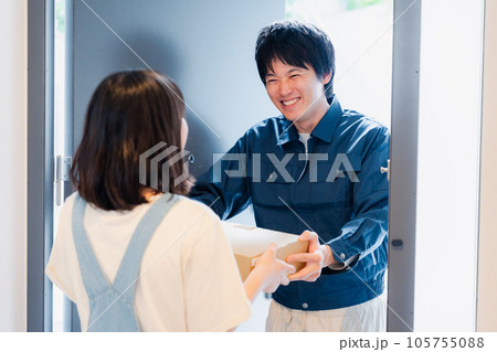 笑顔で宅配便の配達をする若い男性 笑顔で宅配便の配達をする若い男性 105755088