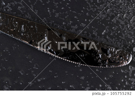 a steel knife covered with water droplets on black paper a steel knife covered with water droplets on black paper 105755292