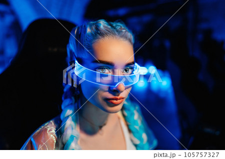 Gamer blogger in neon glasses. Portrait of a young woman in the style of cyberpunk. Gamer blogger in neon glasses. Portrait of a young woman in the style of cyberpunk. 105757327