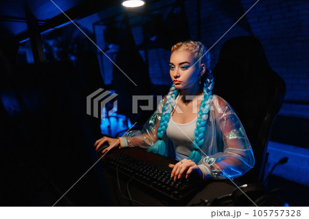 Young female blogger, gamer plays games on computer. Neon computer club. Young female blogger, gamer plays games on computer. Neon computer club. 105757328