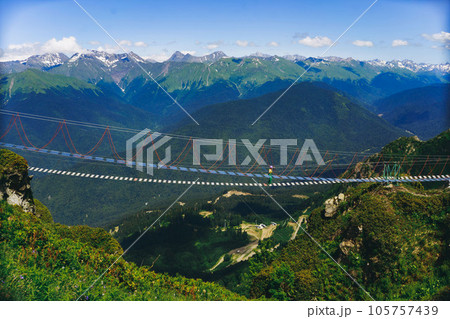 woman rouring walking on rope suspension bridge in caucasus mountains, Russia, Rosa Khutor resort 105757439