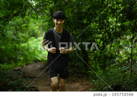 Shot of smiling male athletes running on trail through green forest. Sports motivation, adventure, healthy lifestyle 105758566
