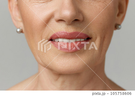 Cropped portrait of elderly smiling woman with copy-space over grey studio background. Dental health. Cropped portrait of elderly smiling woman with copy-space over grey studio background. Dental health. 105758606
