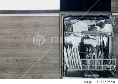 Close-up of opened automatic stainless built-in dishwasher machine inside modern home kitchen with clean utensil. Household, housekeeping domestic life. Household chores, daily home routine, housework Close-up of opened automatic stainless built-in dishwasher machine inside modern home kitchen with clean utensil. Household, housekeeping domestic life. Household chores, daily home routine, housework 105759550