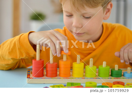 Math game for children. Boy plays with multi-colored rings. Natural materials, wooden. Score, number composition. Home education concept, early development, skills. Math game for children. Boy plays with multi-colored rings. Natural materials, wooden. Score, number composition. Home education concept, early development, skills. 105759929
