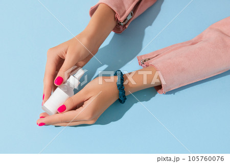 Womans hands holding white cream bottle on blue background. Body care beauty treatment concept 105760076