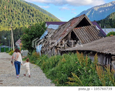 The ruins of an old house in the mountains and a mother and child are walking near the fence The ruins of an old house in the mountains and a mother and child are walking near the fence 105760739