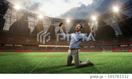 Man standing on knees on football arena, holding mobile phone and celebrating win of money. Successful betting. 3d render Man standing on knees on football arena, holding mobile phone and celebrating win of money. Successful betting. 3d render 105761312