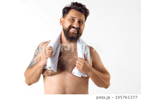 Portrait of handsome, smiling, bearded shirtless man with towel on shoulder smiling against white studio background Portrait of handsome, smiling, bearded shirtless man with towel on shoulder smiling against white studio background 105761377