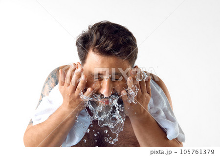 Morning get ready. Bearded shirtless man with towel on shoulders, washing face against white studio background 105761379