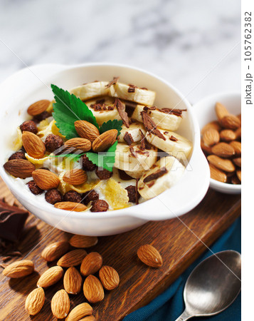 Almond banana salad with chocolate and milk in white plate. Healthy nutritious breakfast. Top view 105762382