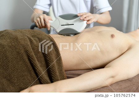 お腹の脱毛の施術を受ける若い男性 105762574