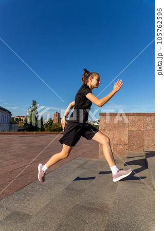 A young woman in black clothes running on stairs 105762596