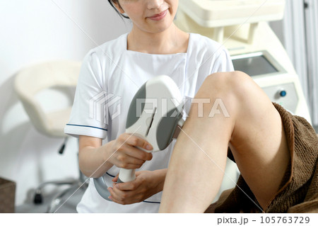 脚の脱毛施術をするセラピストと男性患者 105763729