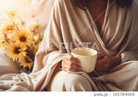 Female hands with a cup of coffee in bed. 105764009